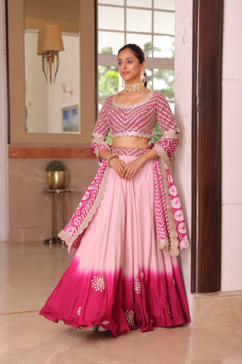 A model is dressed in a pink ombre lehenga with the classic bandhej dupatta.  - By Dishu Sarees (Lehenga to Buy Online) https://dishusarees.com/