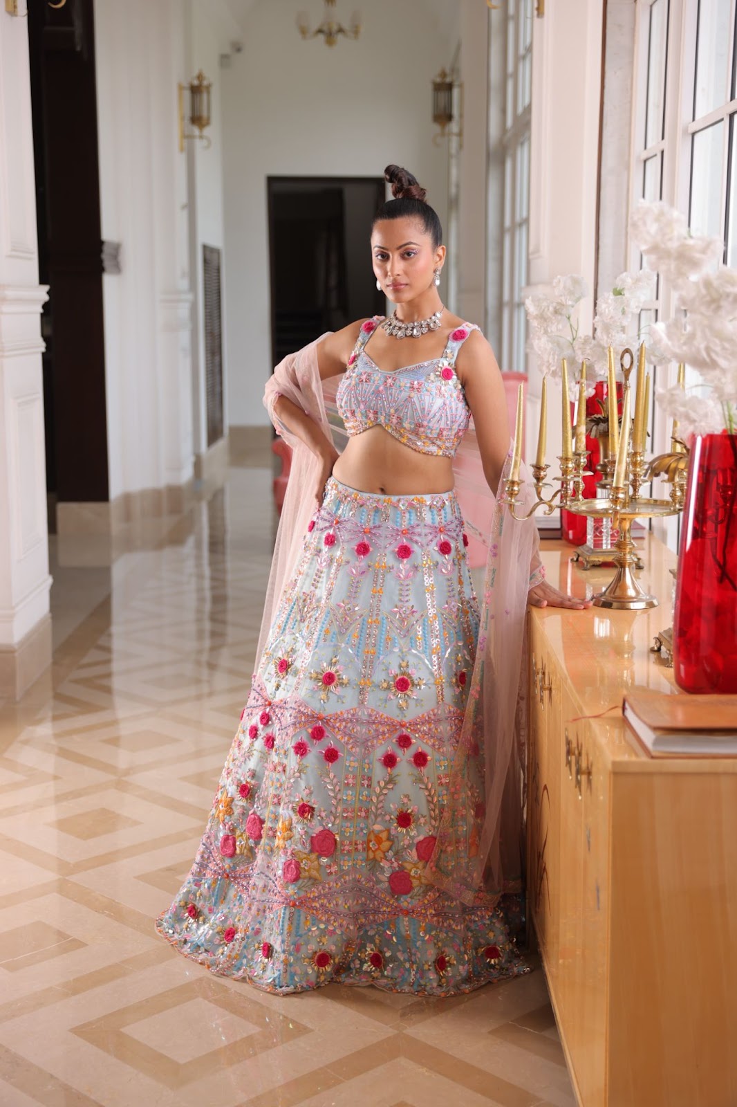 A model wearing pastel blue lehenga with cheerful floral embroidery on it.