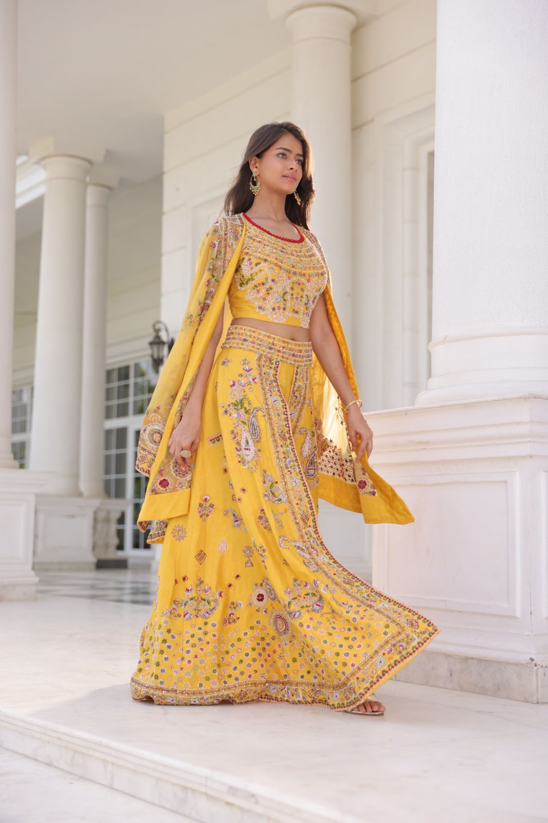 A model wearing boho designed yellow palazzo lehenga with a cape. It has floral embroidery and bead work on it.