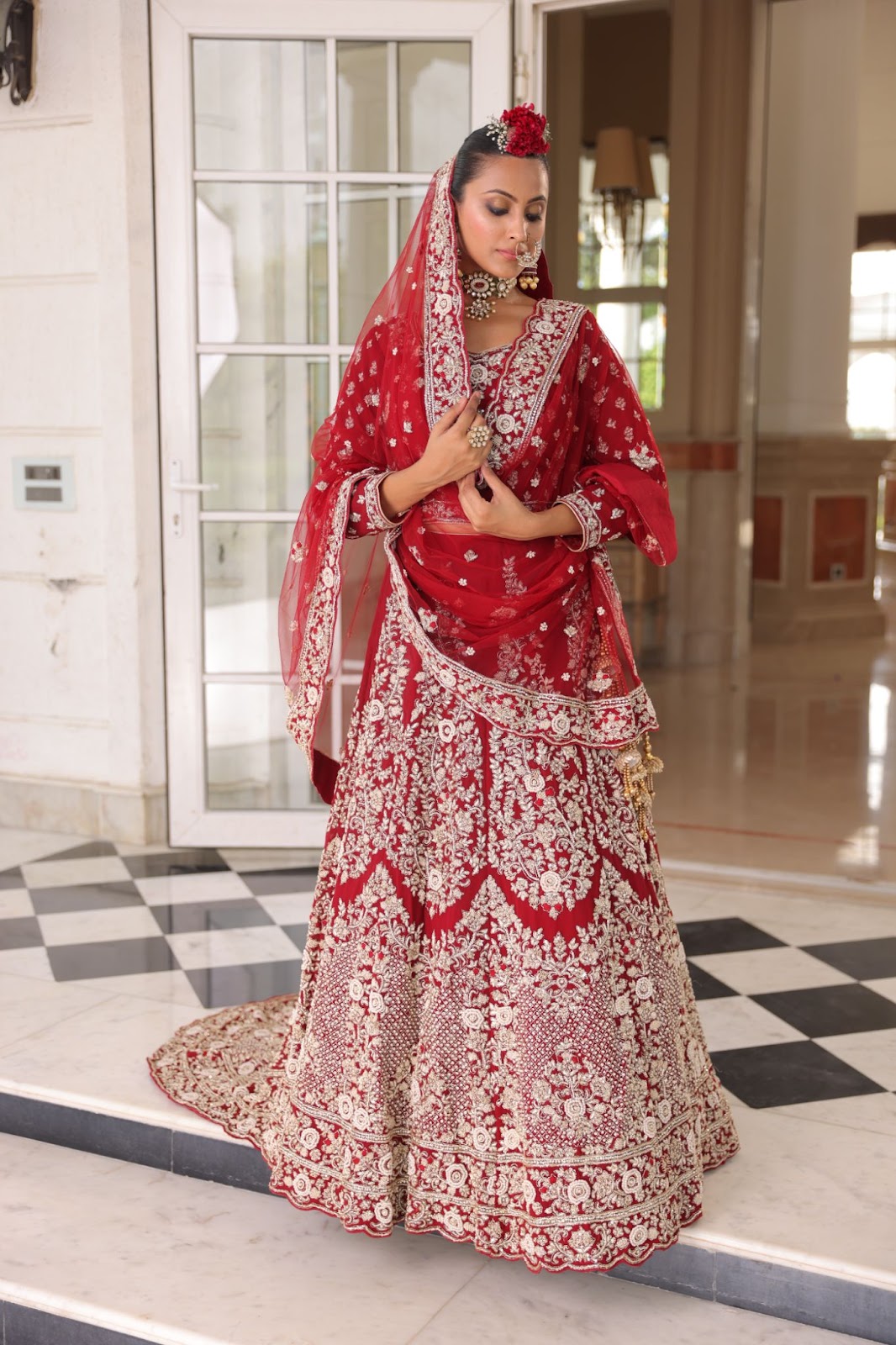 A model wearing bright red lehenga with intricate white embroidery on it.