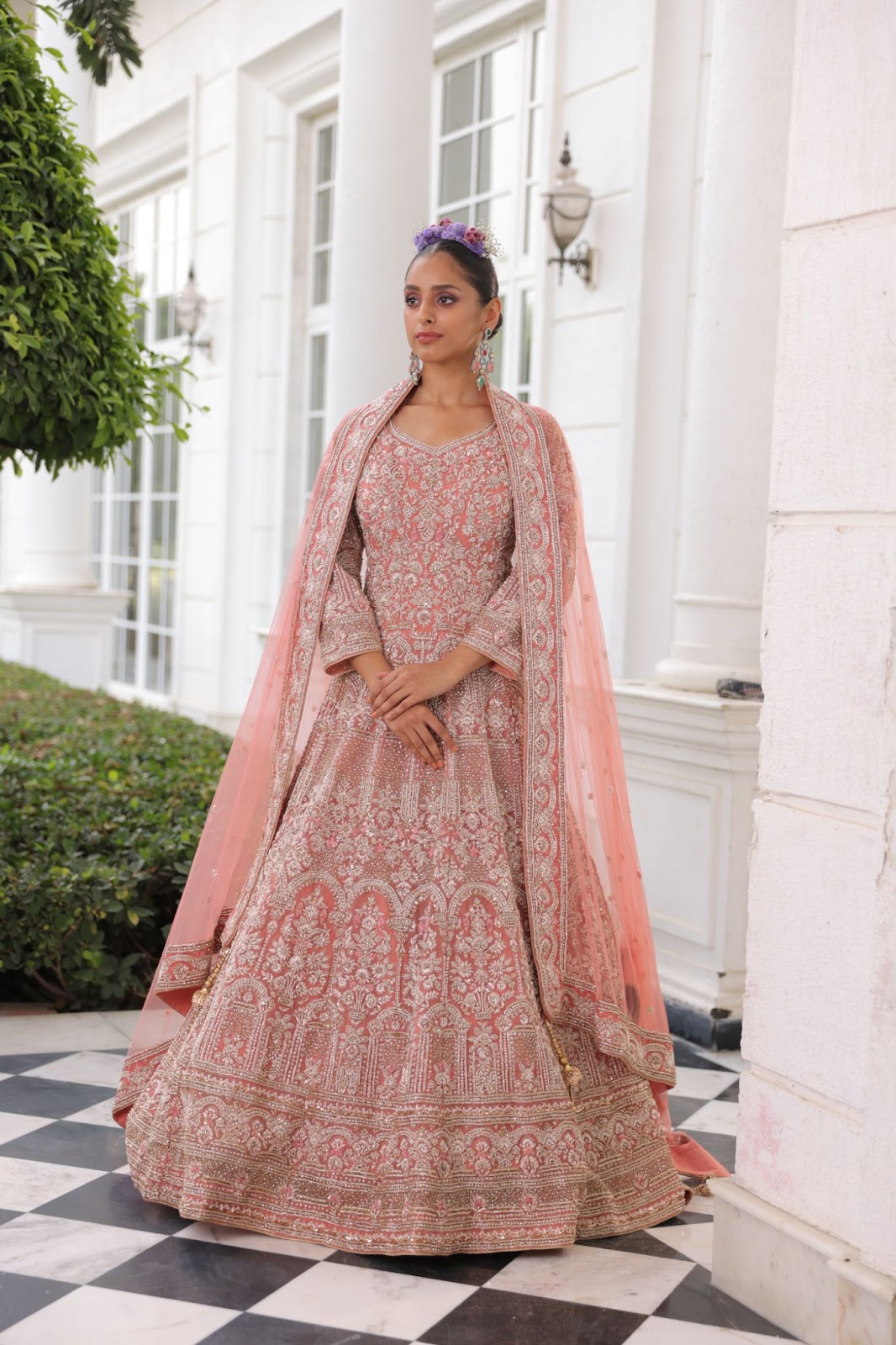 A model wearing peach coloured dress-style lehenga with detailed thread-work and minimal embroidery.